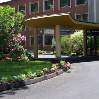 A building entrance with a landscaped garden and driveway.
