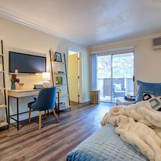 A cozy bedroom with a desk and chair, featuring a wall-mounted TV and stylish decor.