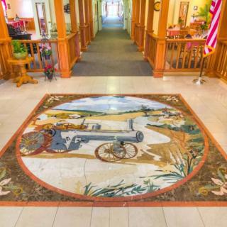 A hallway featuring a large mural on the floor depicting a historical cannon scene.