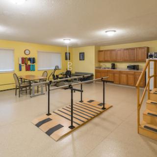 A cozy living space featuring a kitchen and dining area, equipped with exercise equipment and warm yellow walls.
