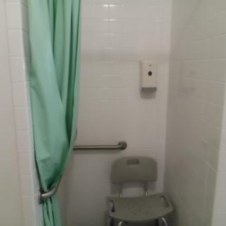 An accessible bathroom stall featuring a toilet and a shower curtain.