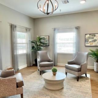 A modern and minimalist living room with neutral tones, showcasing comfortable seating, a central table, and natural light.