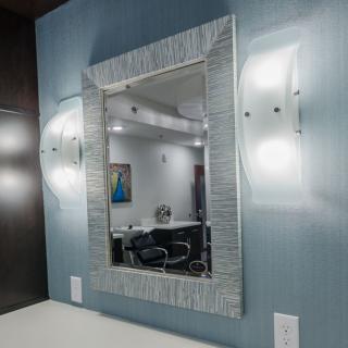 A modern interior featuring a decorative mirror with wall-mounted lights on either side.