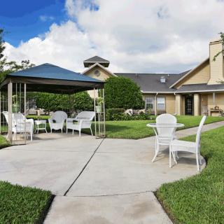 Outdoor patio area with a gazebo, surrounded by green lawns and a house in the background.