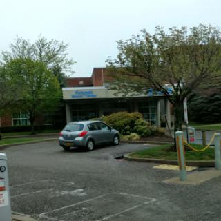A view of a building with a parking lot surrounded by trees.