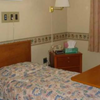 A small hospital room with a bed, nightstand, and a lamp.