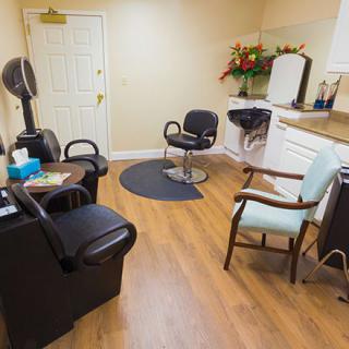 A cozy salon interior with chairs, a hairdryer, and a vanity mirror.