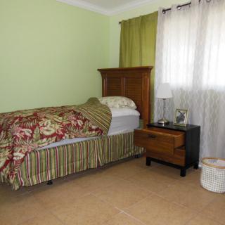 A cozy bedroom with a single bed and nightstand by the window.