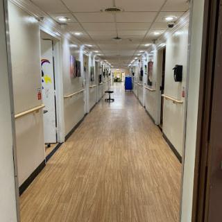 A view of a hospital hallway with doors to various rooms on either side.