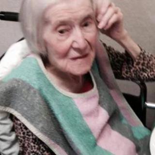 An elderly woman seated in a wheelchair indoors.