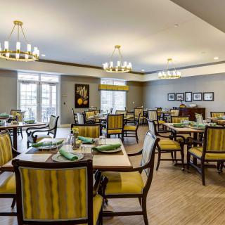 A well-lit dining area with elegantly set tables and chairs, featuring classic decor and ambient lighting.