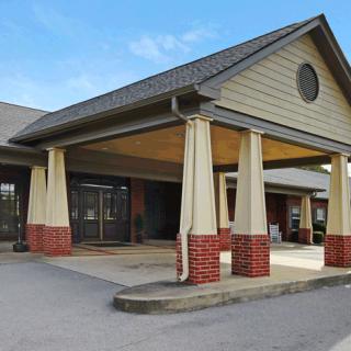 A building with a covered entrance featuring brick and siding, seen during the daytime.