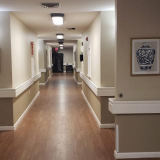 A well-lit hallway with wooden flooring and artwork on the walls.