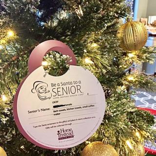 A decorated Christmas tree featuring a charity ornament for seniors.
