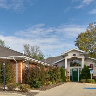 A view of a brick building with a decorative entrance surrounded by greenery.