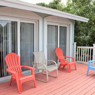 A cozy outdoor deck with colorful chairs and sliding glass doors leading into the house.