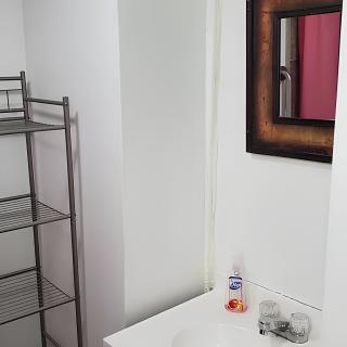 A minimalist bathroom setup featuring a sink, mirror, and metal towel rack.