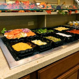 A well-stocked salad bar featuring a variety of fresh vegetables and toppings.