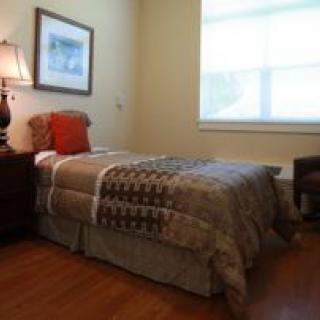 A cozy bedroom with a single bed, lamp, and simple decor.