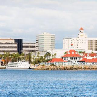 A scenic view of a coastal city with modern buildings and a boat along the waterfront.