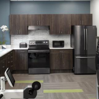 A modern kitchen with dark cabinets and stainless steel appliances, including a refrigerator, oven, and microwave.