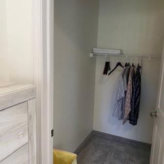 A minimalist closet with a few clothes hanging on a rod.