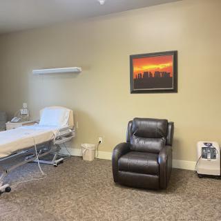 A tranquil patient room featuring a bed, a recliner chair, and calming wall art.
