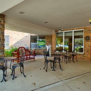 A cozy outdoor caf area featuring wrought iron tables and chairs, perfect for enjoying a meal or drink surrounded by greenery.
