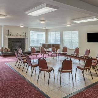 A conference room featuring chairs arranged in a circle with a television and fireplace in the background.