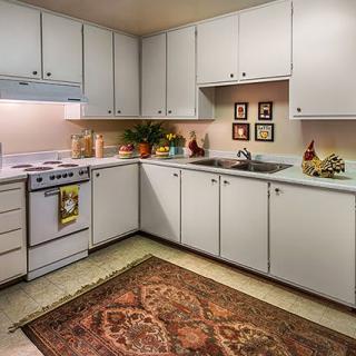 A cozy kitchen with white cabinets, a stove, and decorative items on the countertop.