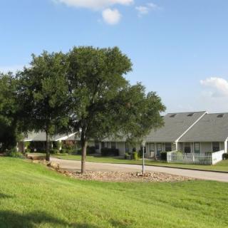 A suburban residential area with houses, trees, and a clear blue sky.