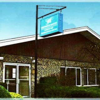 A well-maintained commercial building featuring a prominent sign and landscaped surroundings.
