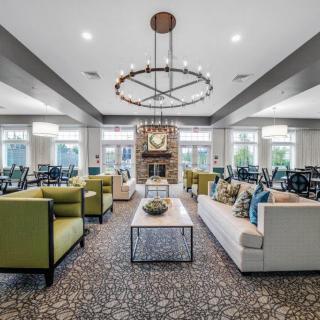 A modern and spacious living room with elegant furniture and a central chandelier.