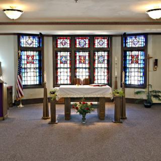 A serene interior view of a chapel featuring an altar and beautiful stained glass windows.