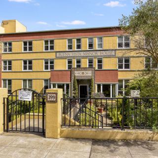 A residential apartment building with a gated entrance and small garden area.