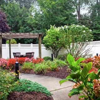 A beautifully landscaped garden with colorful flowers and a pergola providing a shaded seating area.