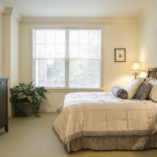 A cozy bedroom with a large window, bed, and decorative elements.