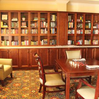 Cozy library reading room with wooden bookshelves and comfortable seating.