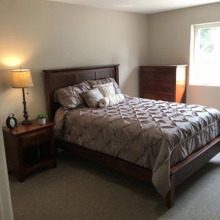A cozy bedroom with a wooden bed, lamp, and dresser.