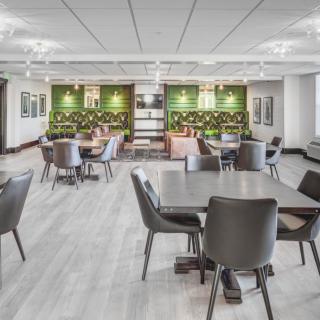 A modern office workspace featuring an open seating area with a green wall and contemporary furniture.