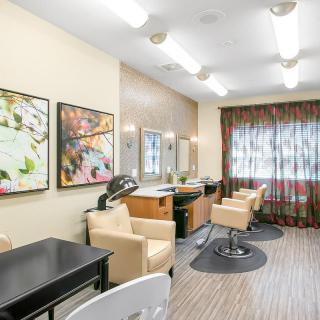 A modern salon interior featuring styling stations, comfortable chairs, and vibrant artwork on the walls.