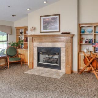 A cozy living room with a fireplace, bookshelf, and comfortable seating.