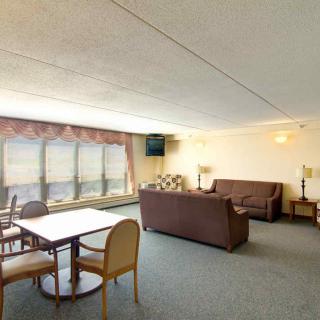A spacious living room with a sofa, dining table, and large windows offering a view.