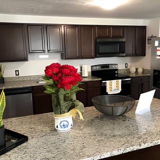 A modern kitchen with granite countertops and decorative flowers on display.