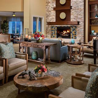 A cozy living room featuring a warm fireplace, surrounded by comfortable seating and elegant wooden tables adorned with decorative accents.