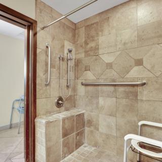A modern, accessible shower with grab bars and tiled walls.