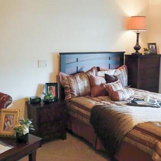 A cozy bedroom with a neatly made bed, bedside table, and warm lighting.