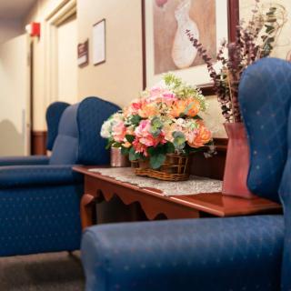 A cozy waiting room with comfortable chairs and a decorative floral arrangement on the table.