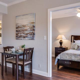 A modern apartment interior with a small dining table near the entrance to a cozy bedroom.