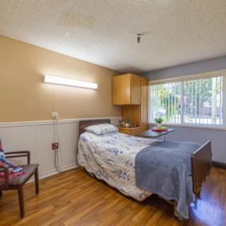 A well-lit bedroom with a single bed, wooden floors, and a window providing natural light.